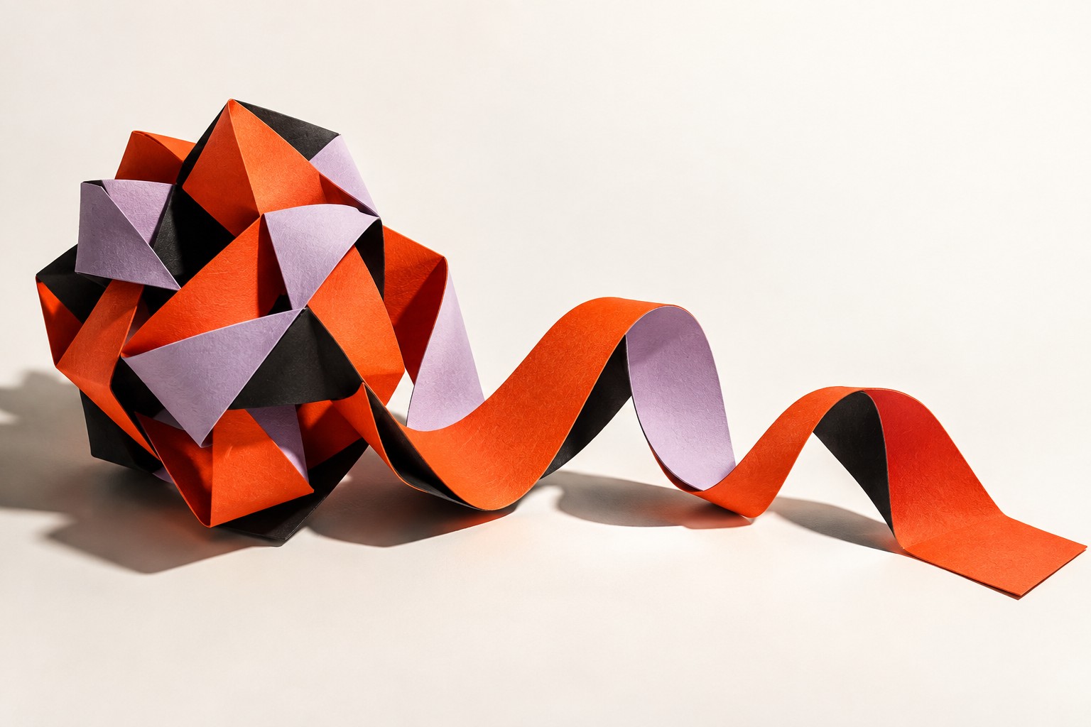 A sculptural ribbon of red and lilac paper unfolding into an open form